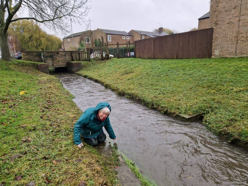 Community volunteer testing for metal pollution in Corby river.