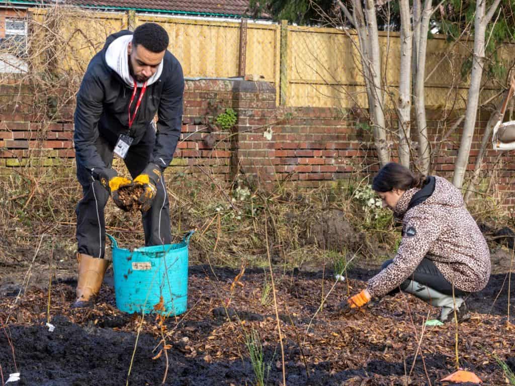 Two people planting tree whips in a Tiny Forest